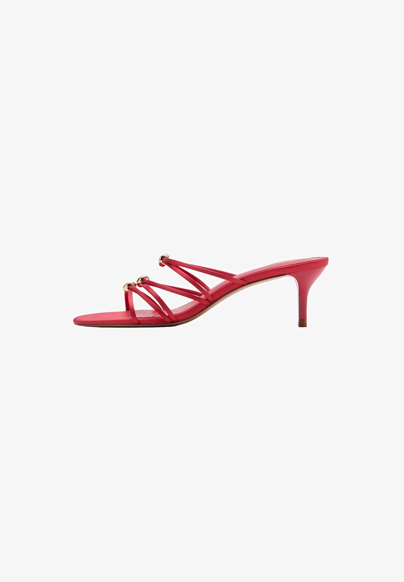 Sandale rouge à bout ouvert à talon avec fines brides croisées et accents anneaux dorés sur un talon aiguilles de hauteur moyenne.