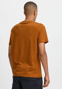 Kortærmet T-shirt i brændt orange, lavet af blødt stof, med rund hals og et enkelt design uden udsmykninger.