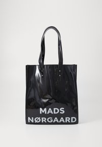 Fekete lakk tote táska dupla fogantyúkkal, elöl nagyméretű fehér felirattal: "MADS NØRGAARD". Simább, fényes felület minimalista kialakítással.
