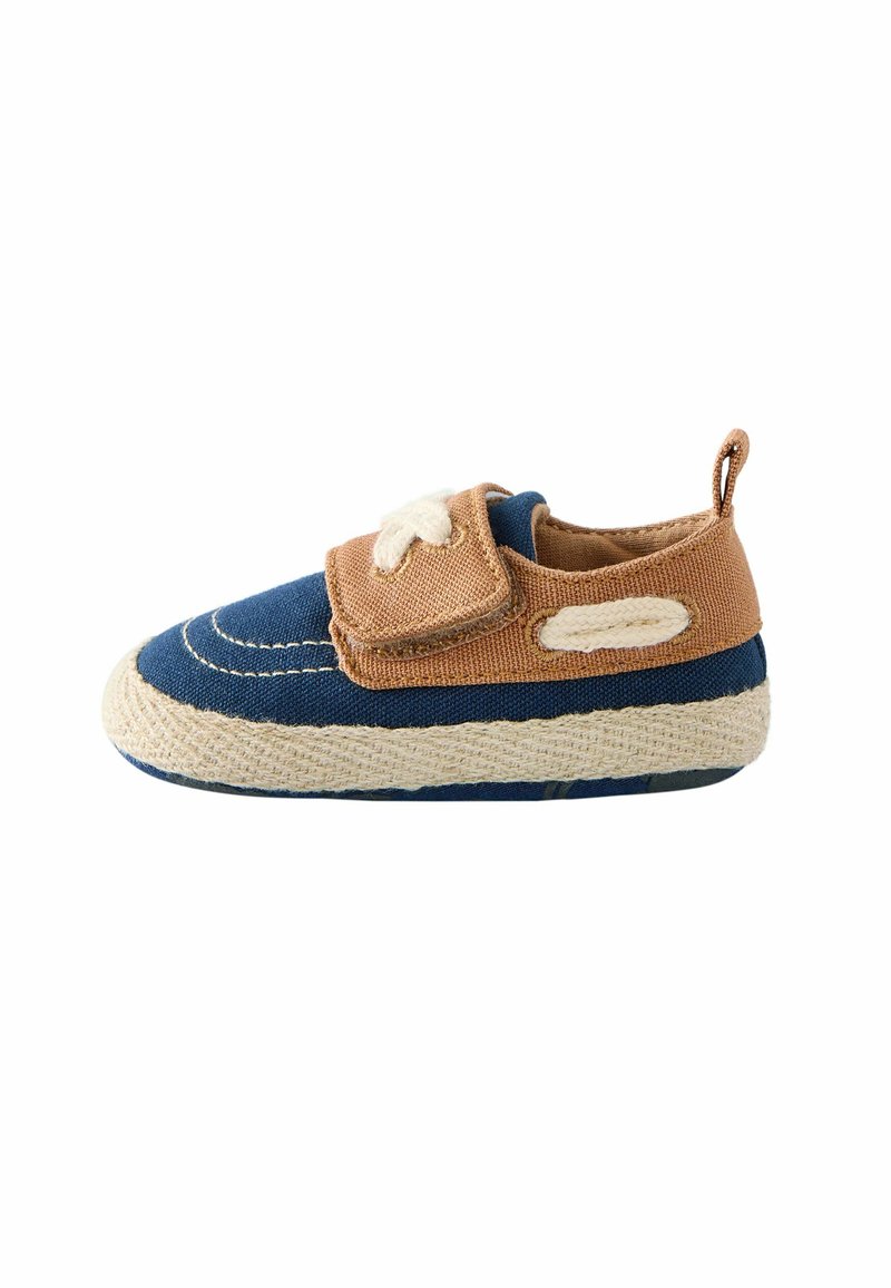 Chaussure en tissu bleu et beige avec une tige texturée, fermetures à lacets et semelle en caoutchouc. Coutures contrastées le long des bords et un petit tablier au talon.