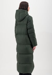 Lange, puffy winterjas in donkergroen met een capuchon, met horizontaal gestikte secties en een gladde, glanzende textuur.