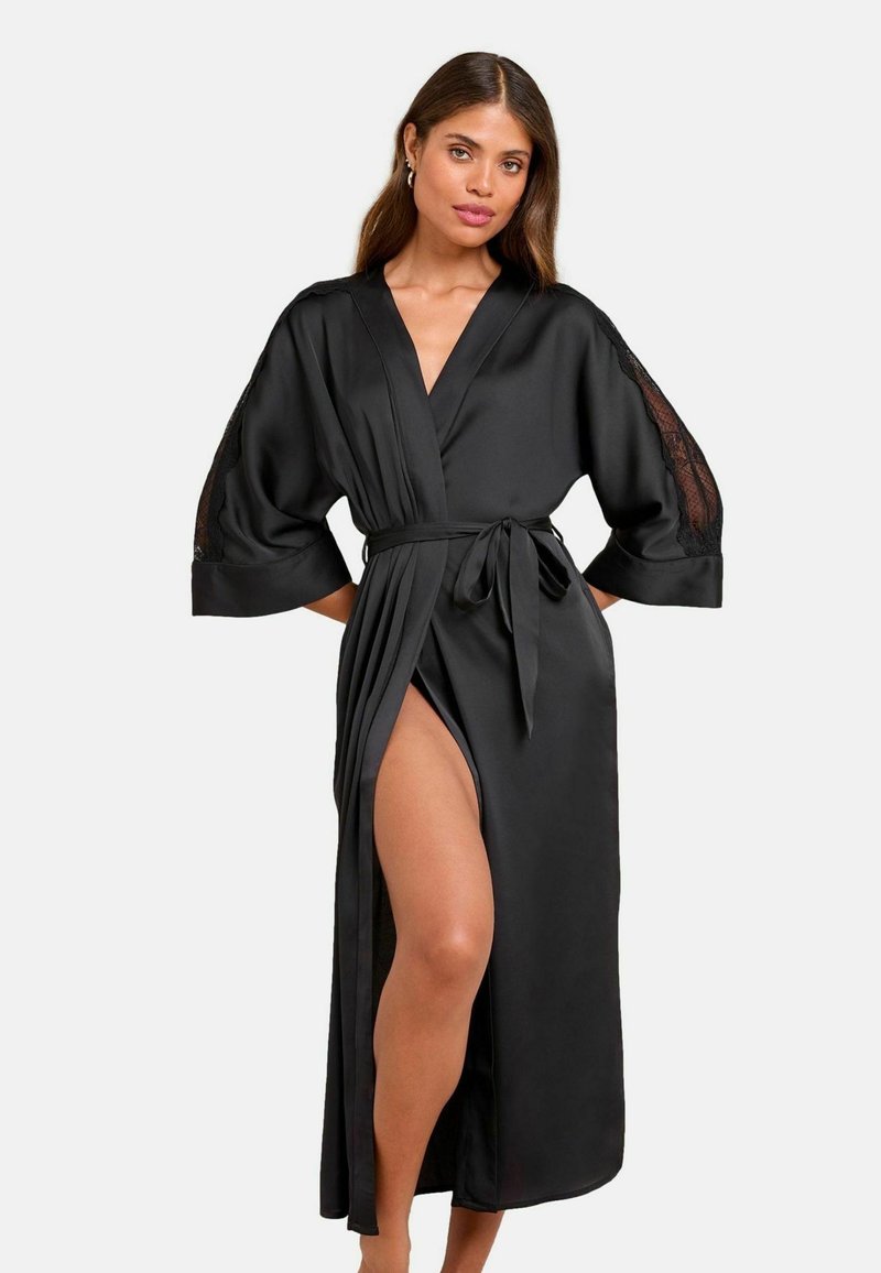 Robe en satin noir avec de larges manches ornées de dentelle, une taille cintrée par une ceinture et une fente haute sur un côté pour plus de détails.