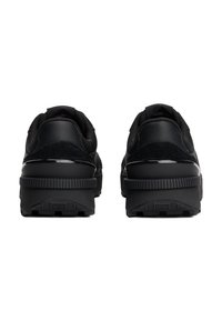 Schwarze Sportschuhe mit einer strukturierten Oberseite aus Mesh- und Wildledermaterialien, einer dicken Gummisohle und minimalistischen Designelementen.