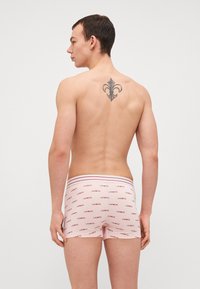 Boxershorts voor heren in lichtroze stof met herhalend rood "LACOSTE"-logo. Voorzien van een contrasterende gestreepte tailleband. Soepele textuur.