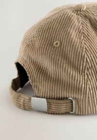 Brown corduroy cap with a textured surface, curved brim, and adjustable strap with a metallic buckle on the back.