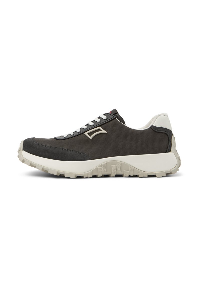 Zapatilla gris oscura con parte superior texturizada, acentos blancos, suela gruesa y cordones grises. Presenta un logo minimalista en el costado.