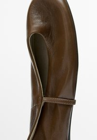 Brown leather Mary Jane shoe with a rounded toe and a narrow strap across the top on a white background.
