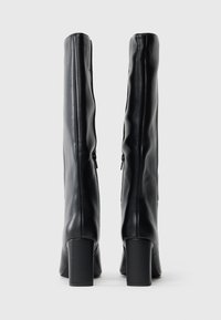 Μαύρες μπότες μέχρι το γόνατο φτιαγμένες από λείο δέρμα, με τετράγωνη τακούνι, πλαϊνούς φερμούς και εφαρμοστή σχεδίαση.