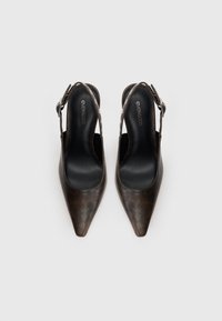 O pereche de pantofi cu toc slingback de culoare maro închis, cu vârf ascuțit și curele ajustabile la glezne, pe un fundal alb.