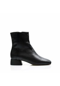 Bota de tobillo de cuero negro con punta afilada, diseño minimalista y tacón corto y grueso. Textura suave con una silueta elegante.