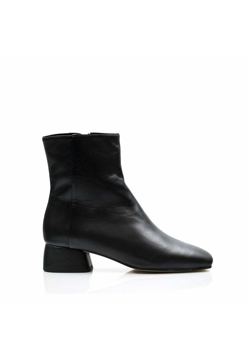 Bota de tobillo de cuero negro con punta afilada, diseño minimalista y tacón corto y grueso. Textura suave con una silueta elegante.