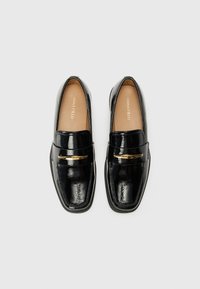 Black patent leather loafers with a square shape, featuring a gold accent across the front and a smooth interior lining.