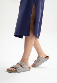 Grijze sandalen met twee verstelbare banden en een kurken voetbed. Het ontwerp heeft een platte zool en een open teen, geschikt voor casual gebruik.