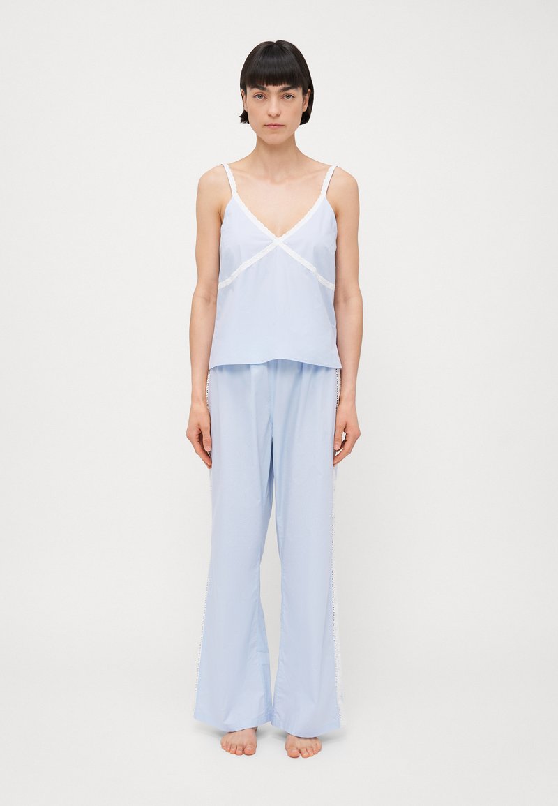 Light blue camisole with lace trim and spaghetti straps, paired with loose-fitting light blue pants, featuring lace accents on the sides.
