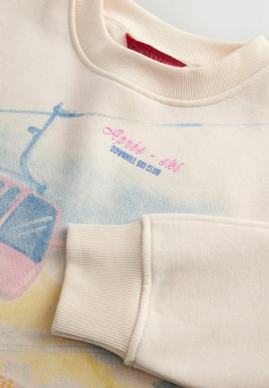 Cream-colored sweatshirt with a soft texture, featuring a scenic print and "Aprés-ski Downhill Ski Club" embroidery in pink and blue.