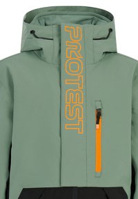 Groene waterdichte jas met een hoge kraag, opvallende oranje "PROTEST" branding, verstelbare capuchon en een ritszak aan de voorkant.