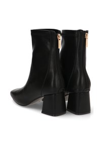 Botas de cuero negras hasta el tobillo con un tacón grueso, textura suave, cremalleras laterales con herrajes dorados y un diseño elegante y ajustado.