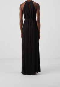 Mustapukuinen hihaton maksimekko, jossa on avokelkkoselkä, istuva vyötärö ja virtaava kangas. Sujuva pinta ja yksinkertainen muotoilu ilman koristeita.