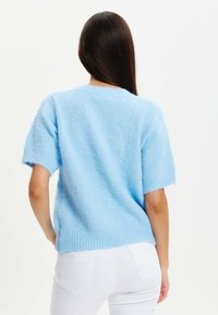 Light blue, short-sleeve sweater in soft, fluffy knit. Features a loose fit and ribbed hem, with a round neckline and minimal detailing.