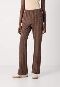 Pantaloni marroni a motivi con vita elastica e strisce laterali. Realizzati in un tessuto morbido, presentano un design geometrico e una silhouette a gamba svasata.