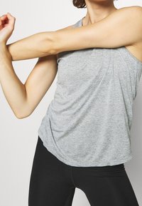 Grå, ærmeløs atletisk tanktop med løs pasform, lavet af let materiale, med rundet kant og subtil meleret struktur.