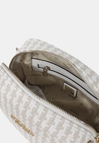Borsa a tracolla intrecciata di colore beige con dettagli bianchi, chiusura a zip e interno foderato che include una tasca con zip e il logo del marchio.