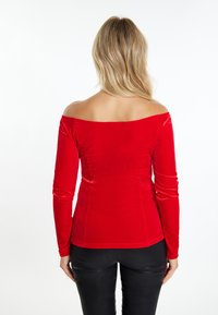 Rode off-the-shoulder fluwelen top met lange mouwen, aansluitend ontwerp, gladde textuur en naadloze afwerking. Geen zichtbare hardware of accenten.