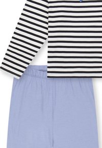 Gestreiftes Langarmoberteil in Schwarz und Weiß über hellblauen Shorts mit elastischem Bund. Weicher Stoff, lockere Passform und minimale Details.