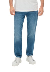 Lichtblauwe denim jeans met een recht gesneden pijp, met een lichte vervaging en wassing details. Draagt met witte sneakers.