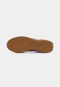 Shoe sole with a textured gum rubber surface, featuring a zigzag tread pattern and a blue synthetic upper edge with brand logo.