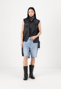 Črn usnjen jopič z ramenskimi epauleti, črn top s pikami, svetlo modre denim kratke hlače in črne usnjene škornje do kolen z zaponkami.