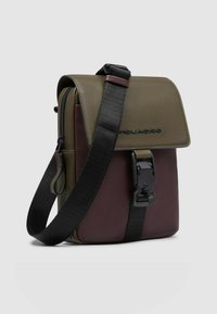 Borsa compatta a tracolla rettangolare in verde oliva e bordeaux, realizzata in materiale sintetico. Presenta una patta frontale e una tracolla regolabile.