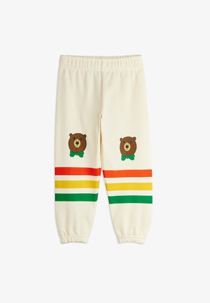 Kremkrāsas sporta bikses ar elastīgām apakšmalām un aukliņu jostasvietā, kurās ir lāču grafikas un daudzkrāsainas horizontālas svītras.