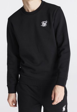 Sweatshirt noir en mélange de coton, doté d'un col rond et de poignets côtelés. Logo blanc brodé distinctif sur la poitrine gauche.