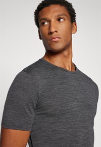 T-shirt cinza de manga curta em tecido texturizado com decote redondo, apresentando um padrão mesclado subtil e uma forma ajustada.