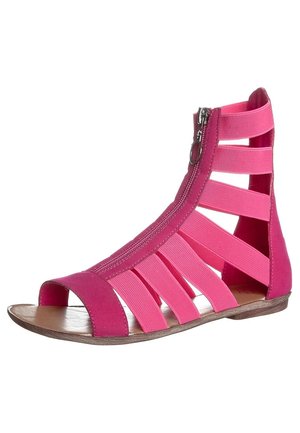 Sandale plate rose de style gladiateur avec plusieurs brides élastiques, bout ouvert à l'avant, fermeture éclair à la cheville et semelle en bois.
