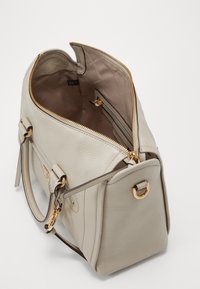 Jasnoszara skórzana torba o gładkiej fakturze, złote okucia, podwójne uchwyty i górny zamek błyskawiczny. Wnętrze wyposażone w kieszeń i materiałową podszewkę.