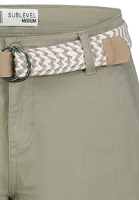 Olivgrüne Hosen mit einem geflochtenen grauen und cremefarbenen Gürtel, der eine runde Metallschnalle aufweist und eine glatte Stofftextur hat, mit dezenten Nähdetails.