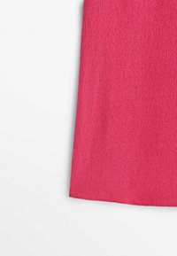 Haut ajusté à manches courtes en rose vif, confectionné dans un tissu tricoté doux et texturé. Il présente un ourlet inférieur net et fini.