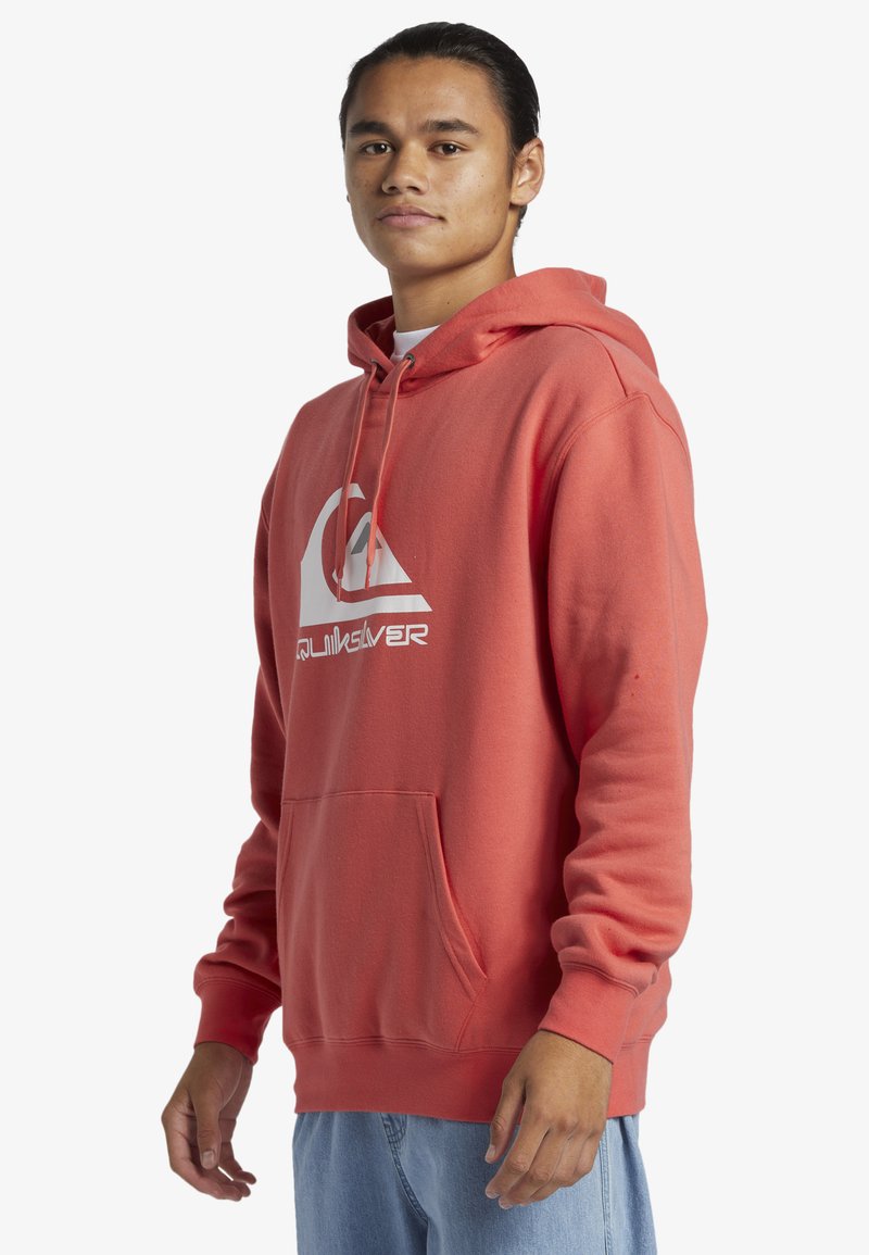 Korálová mikina vyrobená z bavlnenej zmesi, s predným vreckom, nastaviteľnou šnúrkou na kapucni a bielym logom na hrudi.