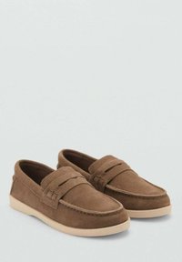 Smeđe suede mokasine s okruglim vrhom, detaljima od šivanja i tamnom gumenom potplatu; sadrže vodoravnu traku preko gornjeg dijela cipele.