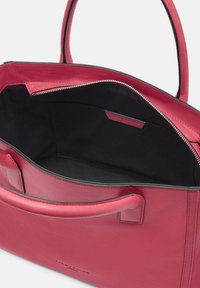 Czerwona skórzana torba na ramię z podwójnymi uchwytami, zamknięciem na zamek i czarną podszewką. Posiada gładką teksturę i minimalistyczny design.