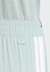 Shorts de sport vert clair avec une ceinture côtelée, présentant des rayures verticales blanches et un logo "ClimaCool" sur le côté inférieur.