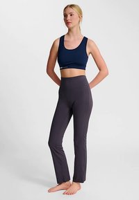 Marinblå sport-bh med breda band, kombinerad med högmidjade mörkgrå leggings som har en åtsittande, slät textur och strömlinjeformad design.