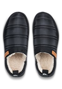 Chaussons noirs à enfiler avec un design matelassé, doublure beige moelleuse et semelle en caoutchouc. Ils présentent un petit accent en cuir marron près de l'ouverture.