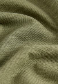 Tessuto di cotone verde oliva con una superficie liscia, che presenta sottili motivi a righe e pieghe morbide e fluenti. Ideale per abbigliamento o tappezzeria.