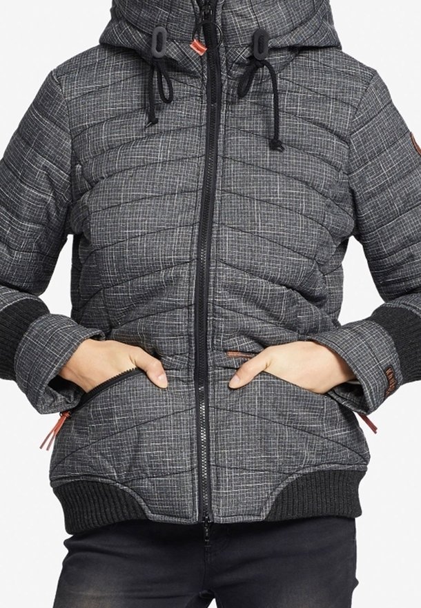 Veste matelassée grise avec poignets et ourlet côtelés noirs, fermeture éclair avant, capuche à cordon de serrage, et mains dans les poches latérales.