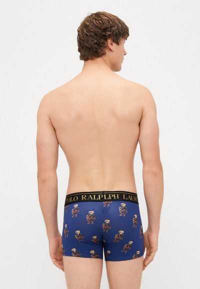 Boxers azules con un patrón de osos juguetones; la cinturilla negra presenta el logo "Polo Ralph Lauren" en dorado. Tela suave y elástica.