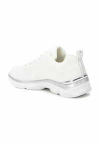 Zapatilla deportiva blanca con parte superior de punto texturizado, punta redondeada y un acento metálico plateado en el talón. Suela suave y acolchada.