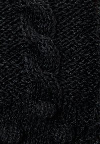 Tessuto in maglia nera con un motivo testurizzato che presenta punti in rilievo e una consistenza morbida e pelosa. Il colore complessivo è un nero profondo.